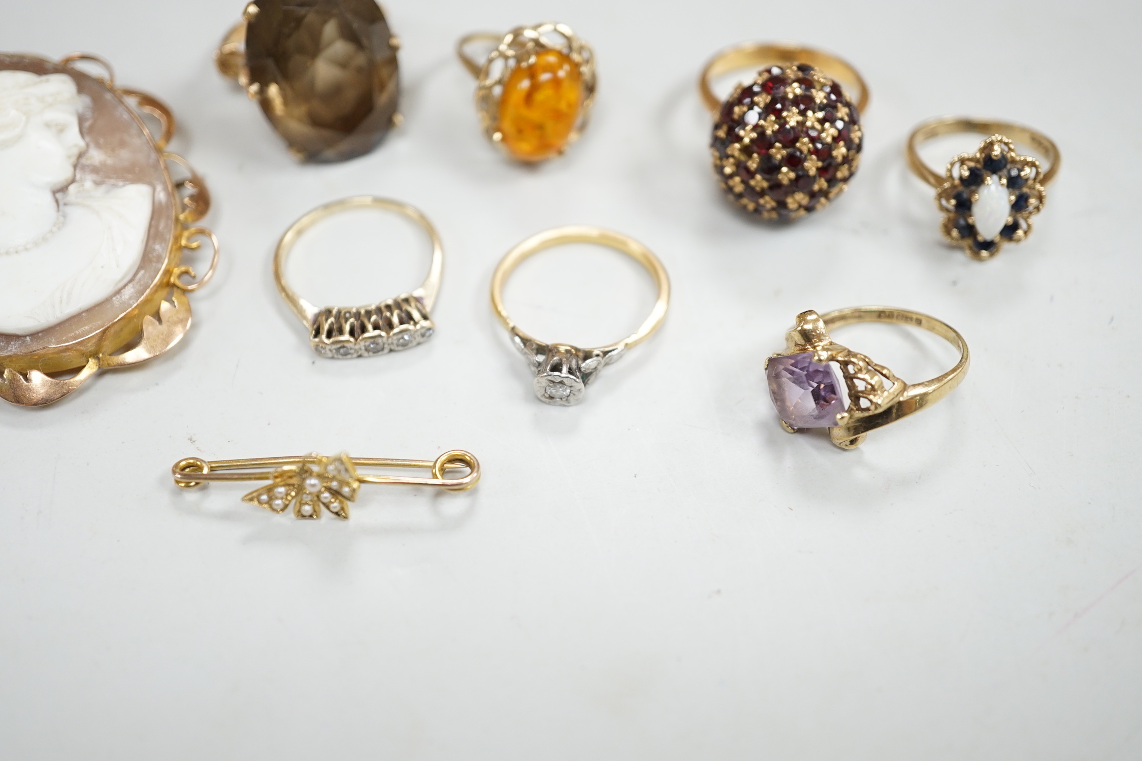 Two yellow metal and illusion set diamond rings, two 9ct gold and gem set rings, two yellow metal and gem set rings and two brooches, including 9ct mounted cameo shell.